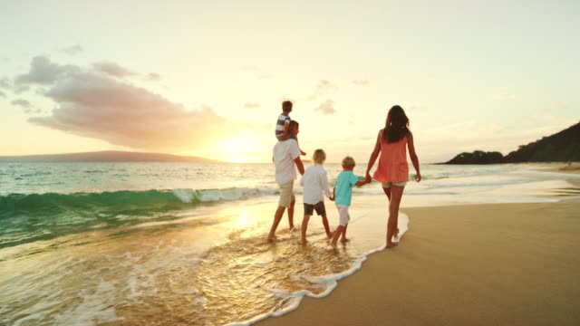 Happy family playing and having fun on the beach at sunset
